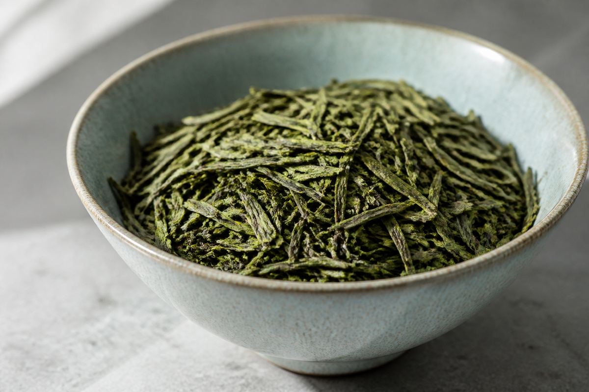 Ceramic bowl filled with dried green tea leaves