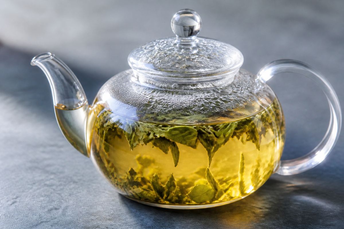 Glass teapot with tea leaves steeping in golden infusion